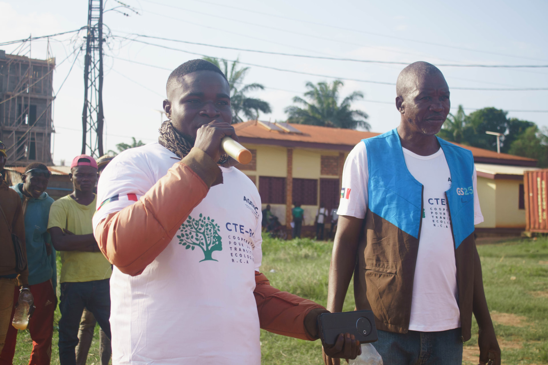 Deux animateurs en t-shirt CTE-RCA mobilisent les habitants dans un quartier de Bangui